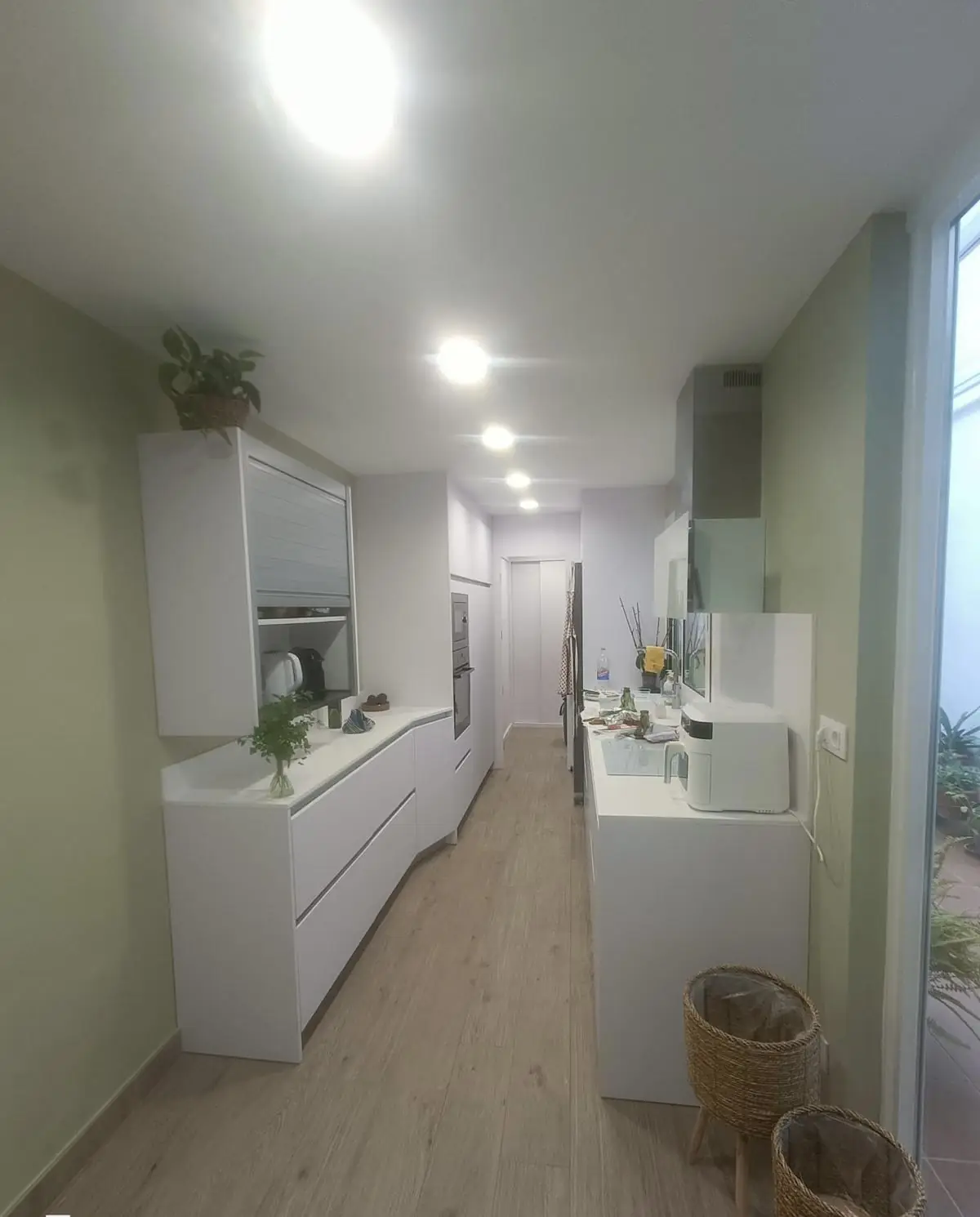 Cocina lineal blanca de suelo a techo en una vivienda reformada