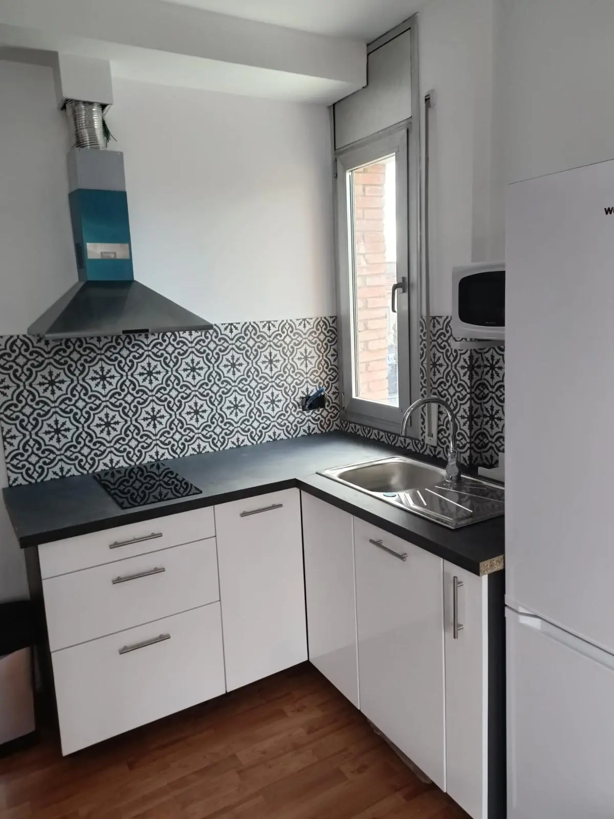 Cocina blanca con encimera negra y frontal de azulejo hidráulico